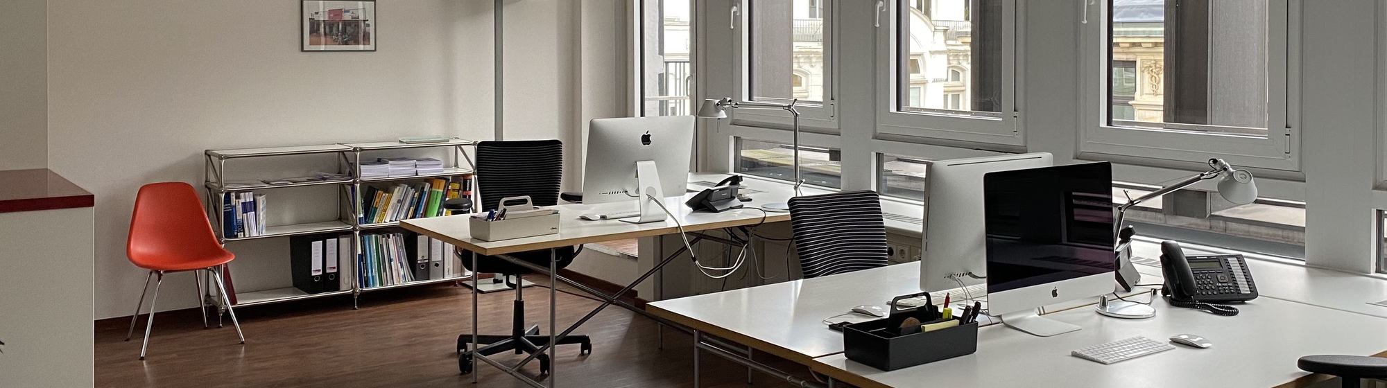 Blick in das Büro von we care communications: zwei Schreibtische, Stühle und ein Regal