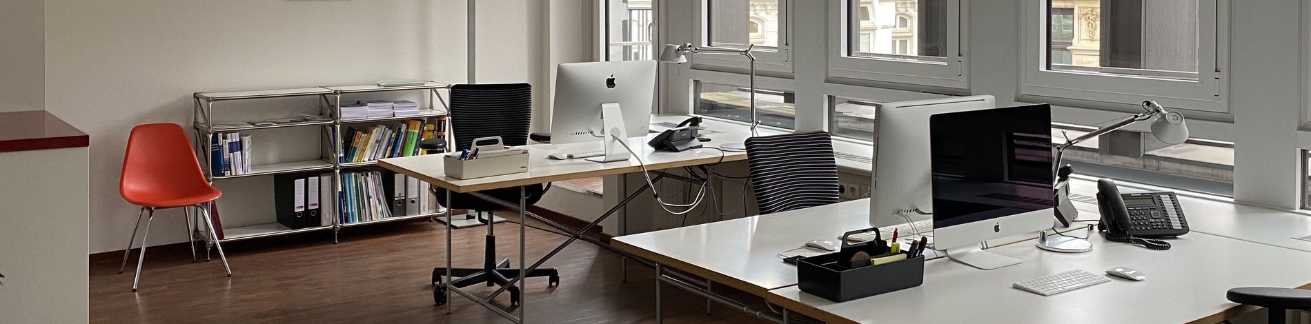 Blick in das Büro von we care communications: zwei Schreibtische, Stühle und ein Regal